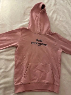 Rosa hoodie från Peak Performance - Säljer en rosa hoodie från Peak Performance i storlek 150. Använd några gånger. Men den har en liten fläck/prick vid trycket. För liten för mig där av säljer jag den. Hade kunnat gå ner lite i pris.❣️