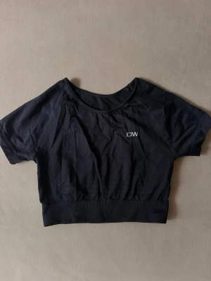 Svart crop top från ICANIWILL - Snygg svart crop top från ICANIWILL med korta ärmar och rund halsringning. Diskret logga framtill och meshdetaljer på ryggen.