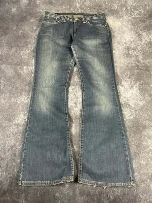Blå Levi’s bootcutjeans för kvinnor i vintage-stil med distressed-tvätt i storlek W29 L30 - Skick: 9,5/10  Midja: 36 cm Benslut: 25 cm Lår: 29 cm Totallängd: 101 cm  W & L är uppskattade utifrån måtten.  Skickas inom ett dygn Spara på priset och frakten genom att sätta ihop ett paket! 1-181