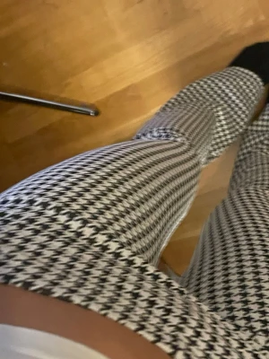 Svarta och vita hundtandsmönstrade leggings - Säljer ett par stretchiga leggings med svartvitt hundtandsmönster. De har hög midja och sitter tight längs benen för en snygg siluett. Perfekta för dig som vill ha ett trendigt och bekvämt plagg till din garderob.