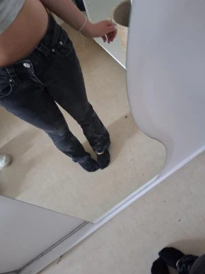 Svarta bootcut jeans med fickdetaljer - Säljer ett par svarta bootcut jeans med coola fickor bak som har vita knappar. Jeansen har låg midja och klassisk femficksdesign framtill. Materialet är denim och passformen är lite utsvängd nedtill. Perfekta för dig som gillar en avslappnad men trendig look.💕