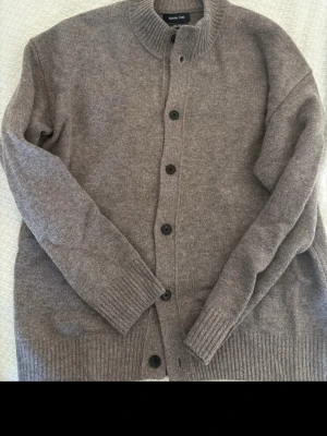 Grå cardiganfrån Massimo Dutti - Snygg grå/biege kofta från Massimo Dutti i 100% ull. Perfekt för lager-på-lager och enkel att matcha med olika outfits. Storlek L men lite liten i storleken.