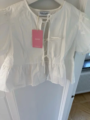 Vit blus från design by amor  - Superfin vit blus från design by amor. Storlek S. Helt ny med lappen kvar, aldrig använd. Köpt för 449 kr.