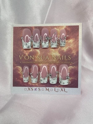 It Girl (S);Medium Square - Snygga handgjorda press-on naglar i nude och vit french med coola silvriga 3D-detaljer och silverpärlor. Naglarna har en medium lång, fyrkantig form och ger en trendig look. Perfekt för dig som vill sticka ut med unika naglar av mig Von Sua.S: 15 mm, 11,5 mm, 12 mm, 11 mm, 9 mm 