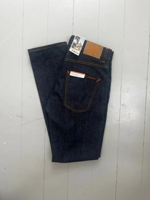 Nudie Jeans Grim Tim Dry Blue  - Helt nya nudie Jeans Grim Tim Dry Blue. Klassiska dry denim-jeans i kraftig, mörk indigoblå denim som formar sig efter användaren med tiden. Alla knappar och sömmar är hela och jeansen är redo att användas. Säljs då passformen inte passade mig. Skickas snabbt och packas väl. Hör gärna av dig om du vill ha fler bilder eller mått.