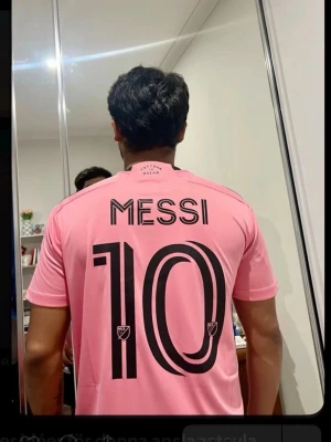 Rosa Messi fotbollströja - Säljer en rosa fotbollströja med Messi och nummer 10 tryckt i svart på ryggen. Tröjan har korta ärmar och klassisk rund hals. Perfekt för dig som vill stötta ditt favoritlag och spelare på match eller träning.