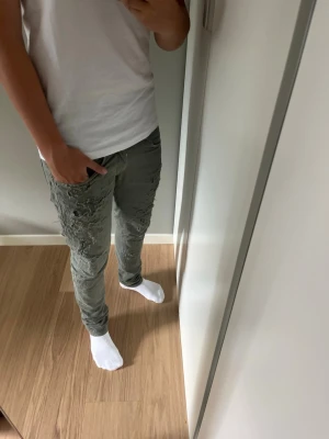 Mörkgröna slitna Dondup George jeans herr - Säljer ett par extremt snygga mörkgröna slim jeans från Dondup med slitningar och trasiga detaljer på både fram- och baksida av benen. Jeansen har klassisk femficksmodell och är tillverkade i jeans material för en tajt passform. Perfekta för dig som gillar en laidback och trendig stil. Jeansen är W31 men passar även W29.Modellen är 179.