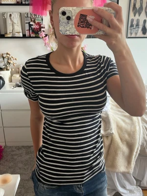 Svartvit randig t-shirt - Säljer en svartvit randig t-shirt med rund hals och korta ärmar. T-shirten har en slim passform och är tillverkad i mjuk bomull, perfekt för en avslappnad och stilren look.