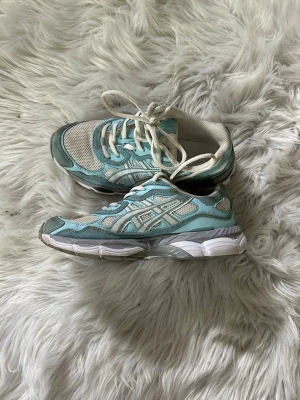 Asics ljusblå och vita sneakers - Säljer ett par fräscha Asics sneakers i ljusblått och vitt med mesh- och syntetmaterial. Skorna har klassisk Asics-logga på sidan, vita snören och en chunky sula i vitt och grått. Perfekta för dig som gillar sportig och retro stil. Som bara har använts i en månad