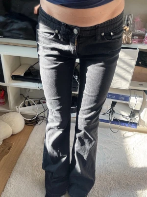 Big star Svarta bootcut jeans med låg midja - Säljer ett par svarta bootcut jeans med låg midja och klassiska fem fickor. Jeansen har en snygg passform som sitter tajt över låren och släpper ut vid bensluten. Perfekta för dig som gillar en retro och avslappnad stil. Storlek 28/32! 