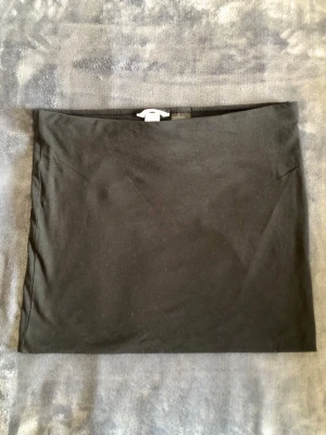 Svart minikjol H&M Basic – Retro/Y2K Strl M - Klassisk svart minikjol i skön trikå från H&M Basic i retro/Y2K-stil! Mjuk och stretchy kvalitet i 95% bomull och 5% elastan med resår i midjan. Enkel att styla till både vardag och fest. Mått: • Midja platt: 41 cm (omkrets ca 82 cm) • Längd: 36 cm Storlek M. Fint skick!