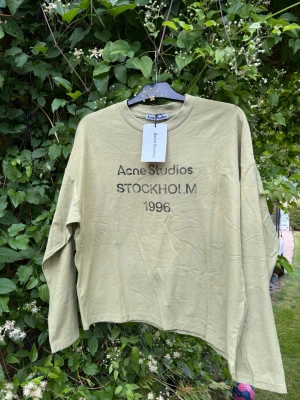Acne Studios Long Sleeve  - Stilren och tidlös tröja från Acne Studios i en fin grön nyans. Ett mångsidigt plagg som är enkelt att matcha och passar perfekt till både vardag och mer uppklädda outfits. 