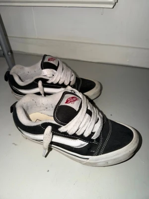 Svarta och vita Vans Old Skool - Klassiska Vans Old Skool sneakers i svart och vitt med vit sula och vit sidostripes. Skorna har lågt skaft, tjocka vita snören och är tillverkade i canvas och mocka. Perfekta för en avslappnad streetwear-look.