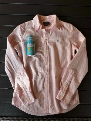 Rosa Ralph lauren skjorta - Säljer en snygg vit och rosa randig skjorta från Ralph lauren! Skjortan är i mycket bra skick och har inga defekter. Om ni har några frågor så hör av er!😊