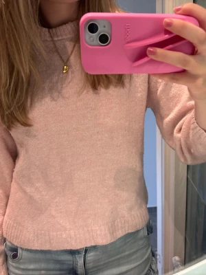 Ljusrosa stickad tröja - Mysig ljusrosa stickad tröja med rund halsringning och långa ärmar. Tröjan har en enkel, klassisk design och är tillverkad i ett mjukt material som känns skönt mot huden. Perfekt att matcha med jeans för en avslappnad look. Lite nopprig men fortfarande jättefin! 