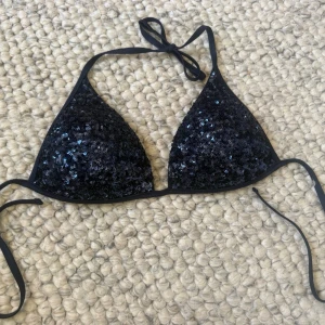 Mörkblå glitter bikiniöverdel  - Snygg trekantsbikini i mörkblå med glittrande paljetter över hela kuporna. Klassisk modell med knyt i nacke och rygg, i push up modellen 