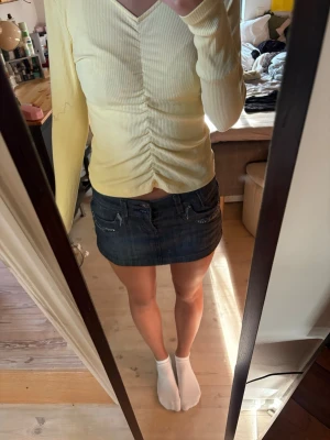 Ljusgul ribbad topp med rynk - Säljer en ljusgul långärmad topp med ribbad struktur och snygg rynkdetalj framtill. Toppen har v-ringning.