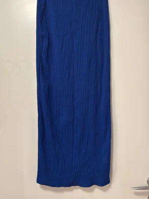 Blå ribbad långkjol Monki - En stilren blå långkjol Monki med ribbad struktur. Kjolen har en rak passform och är enkel att matcha till olika outfits. Perfekt för dig som gillar en clean och modern look. Storlek S, toppskick