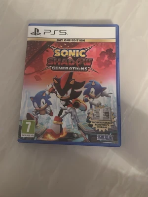 Sonic x Shadow Generations PS5 - Sonic x Shadow Generations Day One Edition till PS5. Fodral i blå plast med färgglad omslagsbild på Sonic och Shadow. Innehåller spel på skiva och bonusmaterial som Gerald Robotnik’s Journal. Perfekt för fans av actionfyllda plattformsspel.