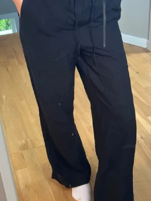 Svarta mjukisbyxor från Gina Tricot - Säljer ett par svarta mjukisbyxor från Gina Tricot med avslappnad passform och dragsko i midjan. Byxorna har raka ben och resår i midjan för extra komfort. Perfekta för chill dagar hemma eller när du vill vara bekväm.