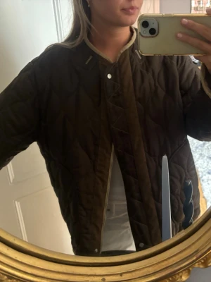  Zara jacka - Säljer en vändbar quiltad jacka i beige och grön från Zara. Jackan har en oversized passform, lång ärm och stängs med dragkedja eller tryckknappar beroende på vilken färg man har utåt. Coola manchester-liknande detaljer! Köpt förra hösten. Använd ett fåtal gånger. 