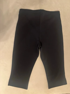 Virala Capri leggings H&M - Säljer ett par svarta croppade leggings med hög midja och stretchigt material. Perfekta för en avslappnad och bekväm stil. Passar till både oversized tröjor och crop tops. Klassisk modell utan synliga detaljer eller fickor. Helt nya slutsålda från H&M