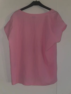 Rosa kortärmad blus från b.young - Säljer en rosa blus från b.young i storlek L. Blusen har korta ärmar och är gjord i ett lätt, strukturerat tyg som ger en avslappnad känsla. Perfekt att styla med jeans eller kjol för en fräsch look.
