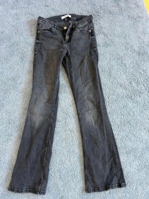 Mörkgrå bootcut jeans - Snygga mörkgrå jeans med bootcut passform och klassiska fem fickor. Jeansen har dragkedjegylf och bälteshällor. Perfekta för en avslappnad och trendig stil. Materialet är denim i bomull.