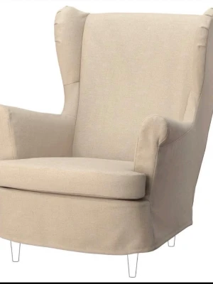 Beige fåtölj - överdrag IKEA STRANDMON - Säljer en beige fåtölj av modellen STRANDMON från IKEA. Fåtöljen har hög rygg, breda armstöd och mjuk sits. Klädseln är i tyg och benen är smala och ljusa. Perfekt för att chilla eller läsa en bok. Oanvända i förpackning, inköpta 2024 men inte blivit använda. Säljes för 300kr / st  