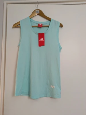 Träningslinne New Balance  - Säljer ett superfint och helt oanvänt träningslinne från New Balance i en fräsch mintgrön/ljusblå färg. Linnet är helt nytt med originaletiketterna kvar (butikspris 799 kr).  Linnet kombinerar stil och funktion på ett perfekt sätt. Framsidan är gjord i mjuk, skön bomull medan hela ryggpartiet är i luftigt och slitstarkt nätmaterial. Nätet är designat specifikt för att ge maximal ventilation och hålla dig sval under löpturen eller gympasset. Linney har lila och vita ränder längs sidorna samt en s