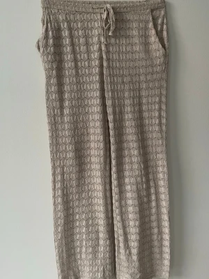 Beige virkade byxor Madlady - Säljer ett par beige virkade byxor från Madlady i storlek XS. Byxorna har  fickor på sidorna och ett snyggt hålmönster i tyget. Perfekta för en chill och avslappnad stil.