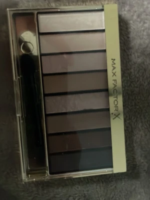 Max Factor ögonskuggspalett nude - Snygg ögonskuggspalett från Max Factor med åtta olika nude- och bruna nyanser. Paletten har både matta och skimrande toner, perfekt för att skapa naturliga eller mer markerade ögonlooks. Kommer i en smidig plastförpackning med applikator.