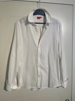 Vit linneskjorta från RYVLS - Klassisk vit skjorta i linne från RYVLS med lång ärm och knappar framtill. Skjortan har en avslappnad passform och mjuk känsla, perfekt för en stilren look. Enkel design utan mönster eller extra detaljer. Storlek 170-176 vilket motsvarar ungefär storlek Small/S🙌