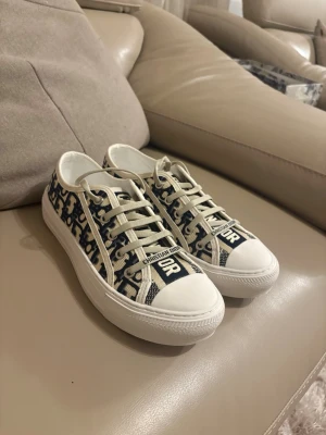 Dior Oblique låga sneakers - Snygga låga sneakers från Dior med klassiskt blått och vitt Oblique-mönster. Skorna har vita snören, vit tå och sula samt tydlig Christian Dior-logga på plösen och sidan. Tillverkade i canvas med gummisula, perfekt för en trendig streetstyle-look.💕💕