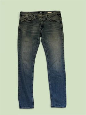 Blå slim fit jeans med slitningar - Snygga blå slim fit jeans med lätt slitna detaljer och klassisk femficksdesign. Jeansen har normal midja och raka ben, tillverkade i denim med en tvättad look. Perfekta för en avslappnad och trendig stil.