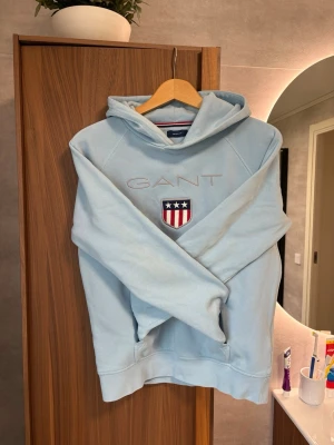 Ljusblå hoodie från GANT - Ljusblå hoodie från GANT i storlek XS Använd ett fåtal gånger och i mycket bra skick.  Nypris: ca 1 300 kr.  Säljs då den inte kommer till användning. Bud är välkomna.
