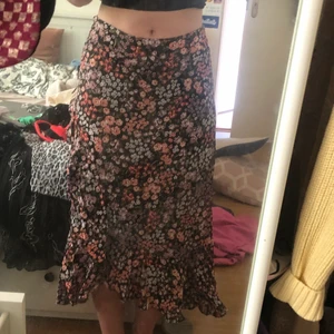 Lång blommig kjol - En lång blommig kjol med volanger längst ner. Den har en dragkedja på sidan. 