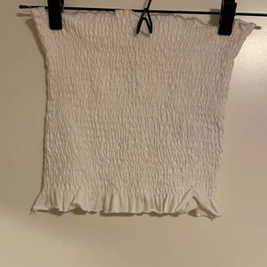 Rynkad bandeau topp från BikBok - Vit tub topp i ett rynkat matrial från bikbok. Säljer då den är för liten för mig, jag har aldrig använt den eller tvättat den men har tagit bort tagen. 