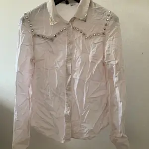 En vit skjorta med coola metalldetaljer som bland annat nitar