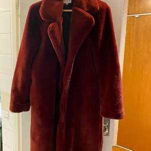Vinröd faux fur kappa från NA-KD - Stl 38 i nyskick, aldrig använd! Skickas med PostNord med billigaste porto, köps via appen och är således spårbart!