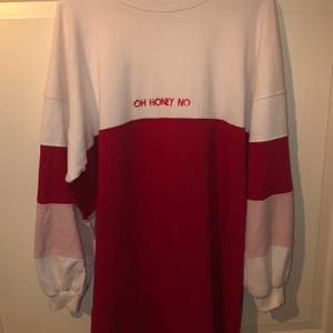 En längre sweatshirt/klänning med röda och rosa detaljer, storlek 48, lite slitage på texten 