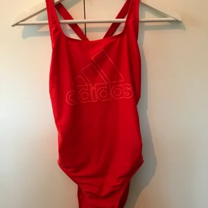 Röd baddräkt - Jättefin röd baddräkt från adidas med nästan hel öppen rygg! Storlek 34/XS och har endast använts 2ggr och är i NY SKICK. Säljer pga att den inte kommer till användning. Köparen står för frakten och jag vet att den är dyr, därför är priset på plagget sänkt!