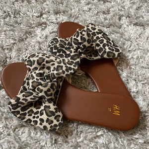 Sandaler/Tofflor - Supersnygga sandaler/tofflor från H&M. Rosett i leopardmönster, perfekta till sommaren😍 De är aldrig använda så de är precis som nya! Storlek 37 men skulle nog även passa 36🥰