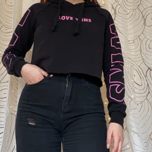 Svart croppd hoodie - Jättemysig croppd hoodie med trycket ”love wins” på både bröst och armar, från gina tricot. Har inte använt den alls mycket. Den är lite nopprig på insidan men fortfarande väldigt mjuk och len. Utsidan är inte alls nopprig. 