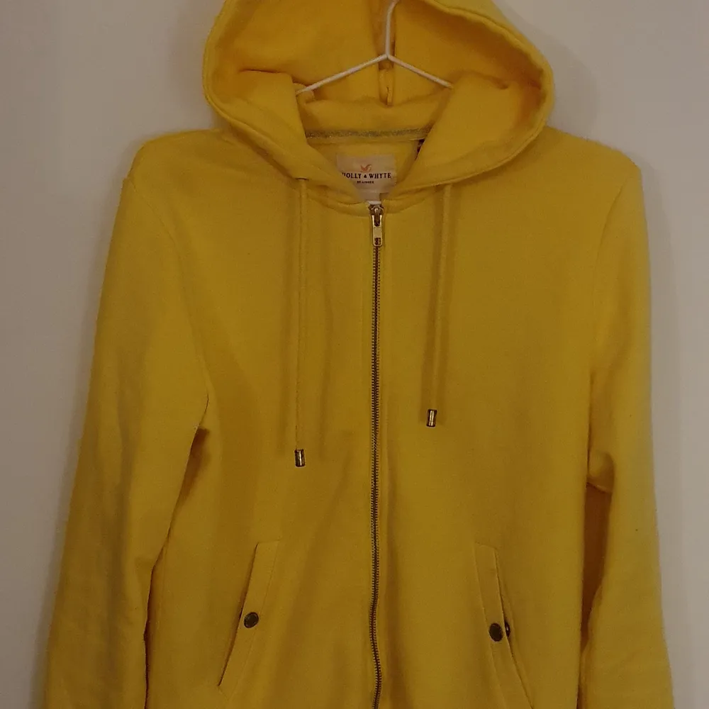 En zipup-hoodie från Holly & Whyte i en glad gul färg med guldfärgade detaljer. Sparsamt använd, inga fläckar eller liknande. Pris kan diskuteras vid snabb affär. Hoodies.