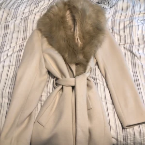Beige kappa från H&M - Falskt päls - Denna fina beige kappa är från H&M och är köpt för cirka 2 år sedan. Använd 2 gånger och har inga skador, är i helt nyskick. Falskt päls. Jackan är i  storlek - 36/S