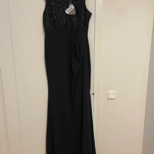 Svart klänning  - Oanvänd klänning, super fin. Storlek 16 UK kan vara XL. Frakt ingår i priset. Möter inte upp.