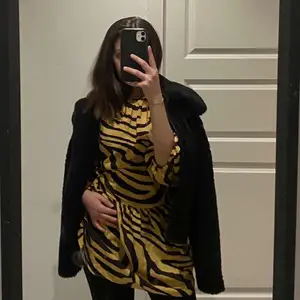 En superfin klänning i ett svart och gult zebramönster. Den passar utmärkt till exempelvis en natt på stan eller en fin middag med familjen. Plagget är i mycket bra skick!
