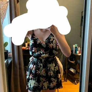 Divided (H&M) strl 36 - En kortbyxdress med linne upptill. Luftig till sommaren. Den är svart med exotiska blommor på. Sitter löst/pösigt på och även inte för korta i nedredelen. Aldrig använd med prislapp kvar då jag inte tyckt om hur den ser ut på mig. Storlek 36 och sitter väldigt bekvämt på med linneband som går att justera. Original pris 149kr