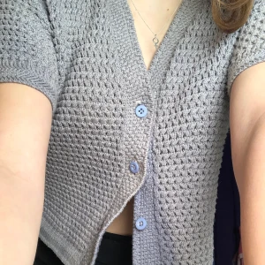 stickad kortärmad cardigan - en lite croppad, stickad cardigan i gott skick. hittar inte storlek men passar bra på mig som är S. saknar knapp längst ned men själv använder jag den ändå inte (går självklart att sy fast en ny också:)). köpt second hand. hör av dig!!💖